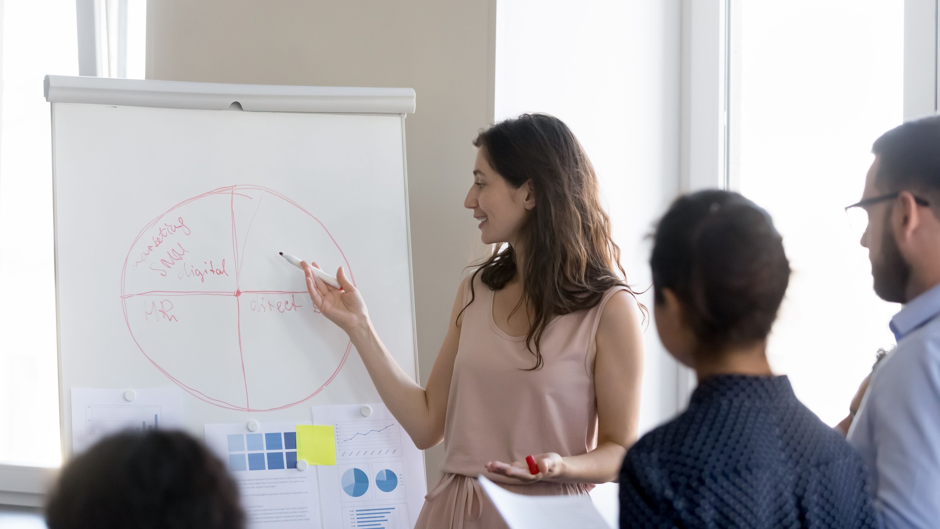 Trainer give presentation on flip chart to diverse company employees
